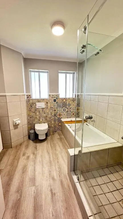 Bathroom with a tiled tub, patterned mosaic splashback and a separate glass-enclosed shower