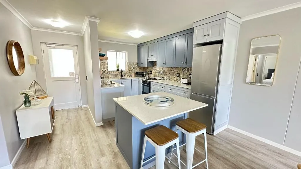 Renovated kitchen with pale grey cabinetry, a quartz island and a stainless steel fridge