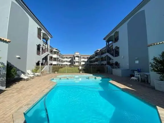 Communal L-shaped pool framed by the mews' three-storey balconied units and a section of lawn