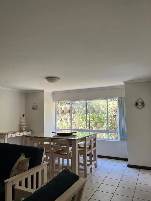 Dining table for four beside a large window overlooking leafy garden greenery