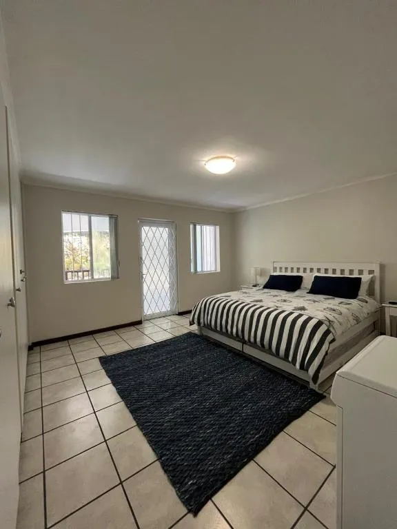 Double bedroom with striped navy bedding, twin windows and a burglar-barred door onto the garden