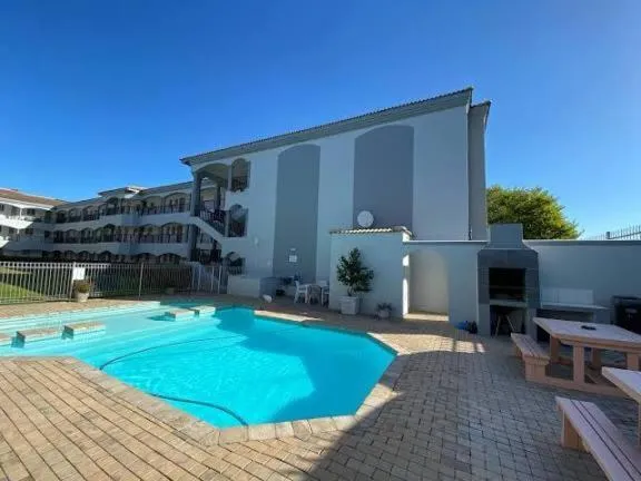 Shared courtyard pool with sun loungers, a built-in braai station and picnic table at the mews complex