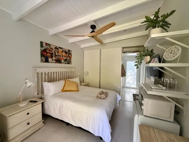 Studio bedroom with vaulted beamed ceiling, sliding wardrobe and a kitchenette corner