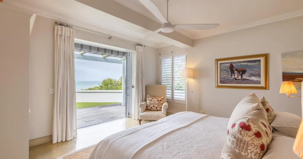 Bedroom opening onto a private balcony over a lawn strip with sea beyond