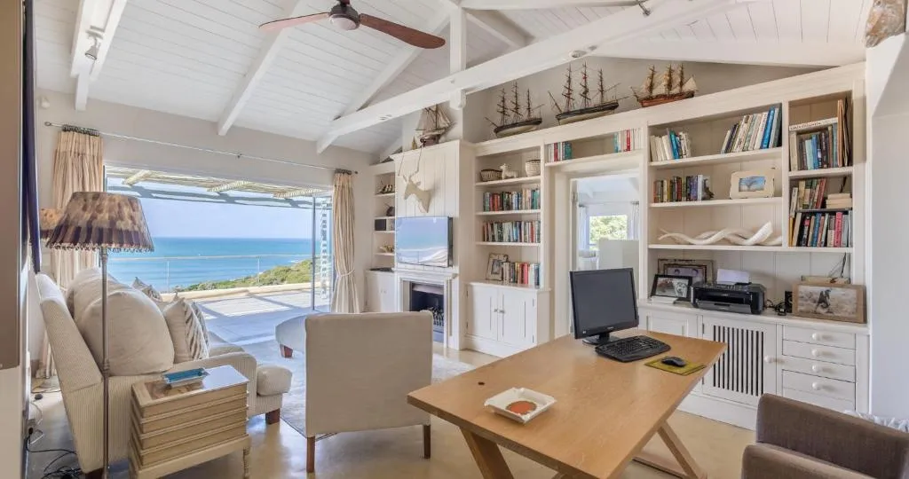 Home office nook with built-in bookshelves and a full ocean view through sliding doors