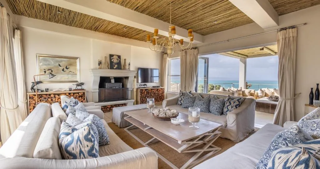 Open-plan lounge with reed ceiling, fireplace and sliding doors onto an ocean-view terrace