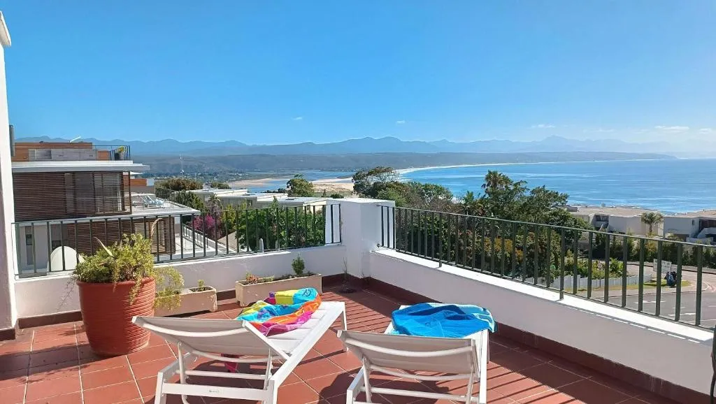 Rooftop terrace with sun loungers overlooking Lookout Beach and the ocean toward the mountains