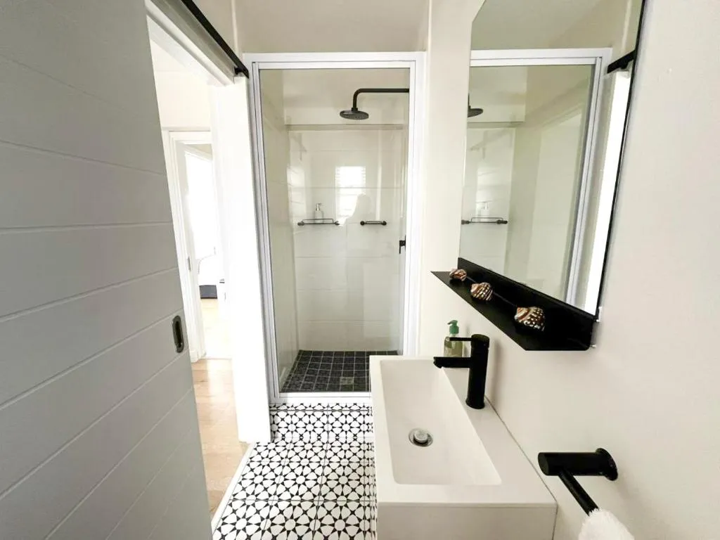 Bathroom with glass shower, black fittings and patterned tile floor