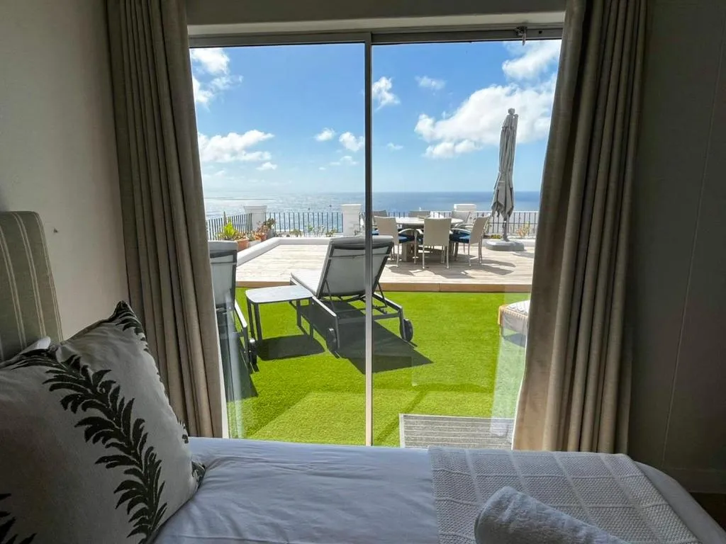 Bedroom sliding door opens onto the terrace with the ocean beyond