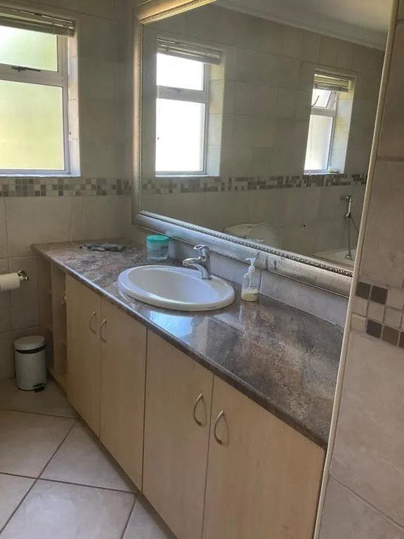 Bathroom with a stone-effect vanity counter, single basin and a large mirror