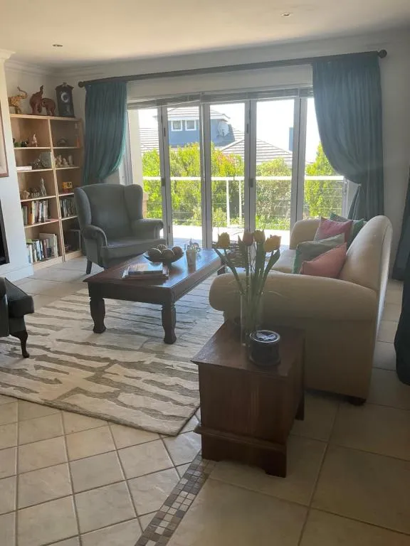 Living room with teal curtains, a wingback chair and sliding doors opening onto a balcony