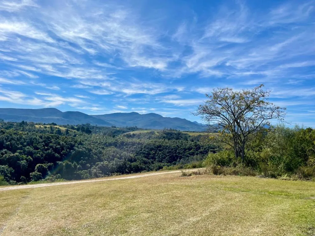 View across a grassed clearing to forested hills and mountains surrounding the farmhouse