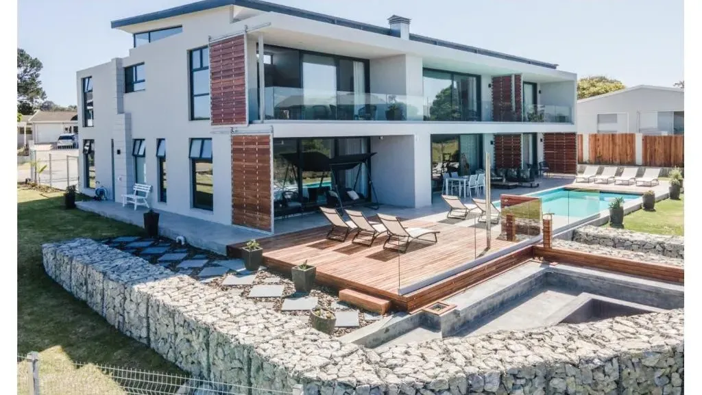 Modern white apartment building with a timber sun deck and swimming pool on the lawn