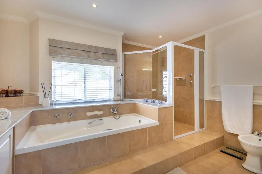 En-suite bathroom with a corner bathtub beneath a window and a separate glass shower cubicle