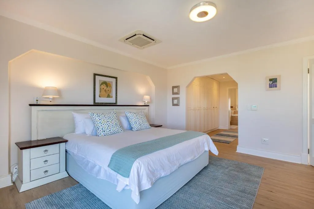 Bedroom with a ceiling cassette air conditioner, built-in wardrobe, and doorway to an en-suite