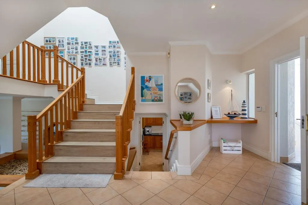 Entrance hall with a wooden staircase, tiled floors, and a gallery wall of framed photos