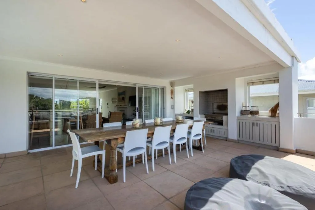Covered patio dining area beside sliding doors and a built-in braai station
