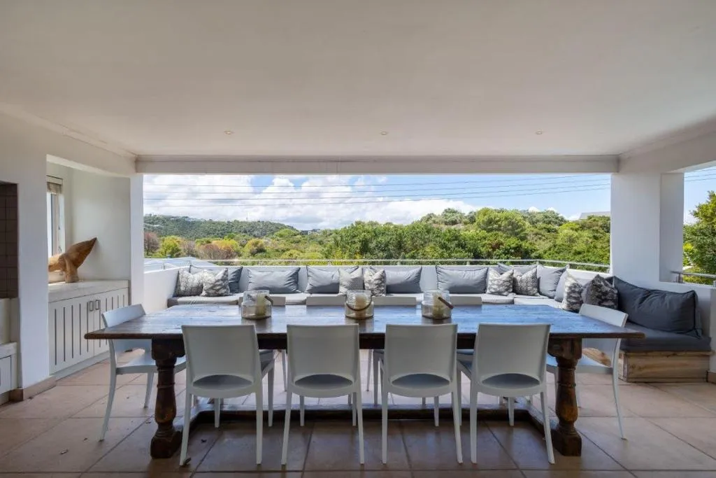 Covered patio lounge and dining area overlooking forested hills from the upper level