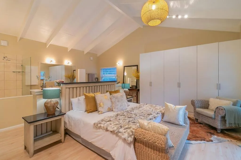 Vaulted-ceiling bedroom with a king bed, built-in wardrobes, and an open ensuite bathroom