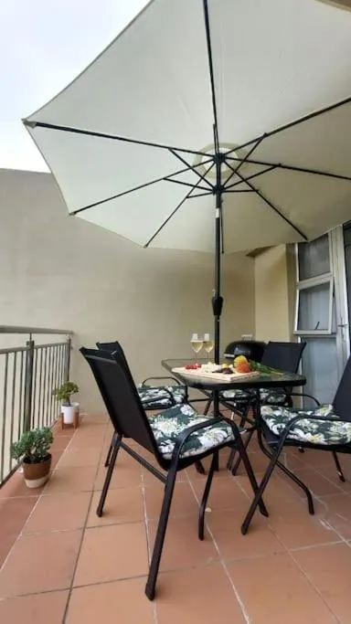 Outdoor dining table for four under a cream umbrella on the tiled balcony