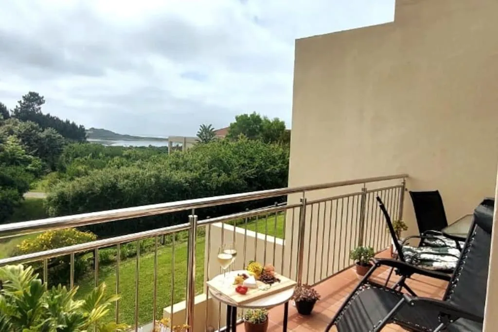 Balcony railing view across garden and coastal bush to the lagoon in the distance