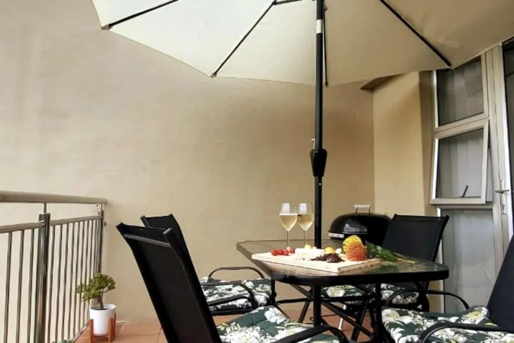 Wine glasses and a cheese board on the balcony table beside the kettle braai