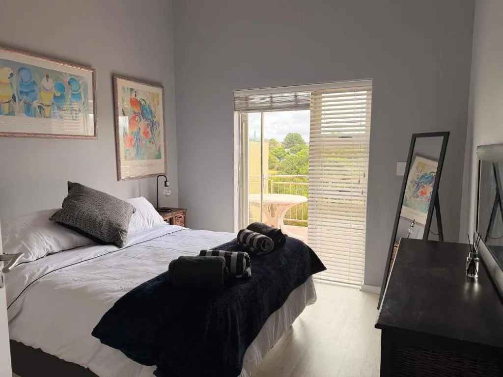 Main bedroom with a navy throw and sliding doors onto a private balcony with a bistro table