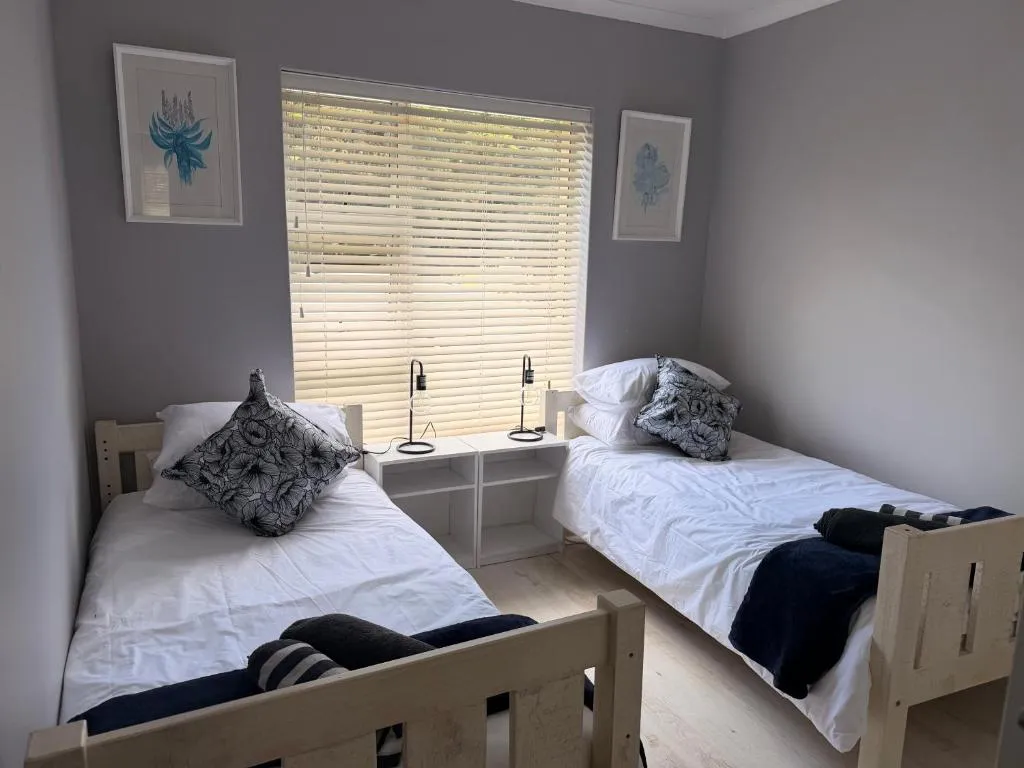 Twin bedroom with wooden bed frames, floral artwork and closed blinds