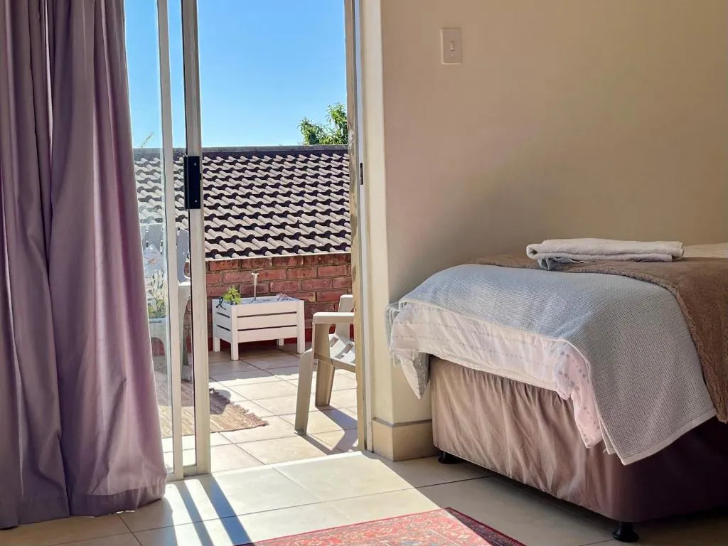 Bedroom with a sliding door onto a tiled balcony beneath the roofline