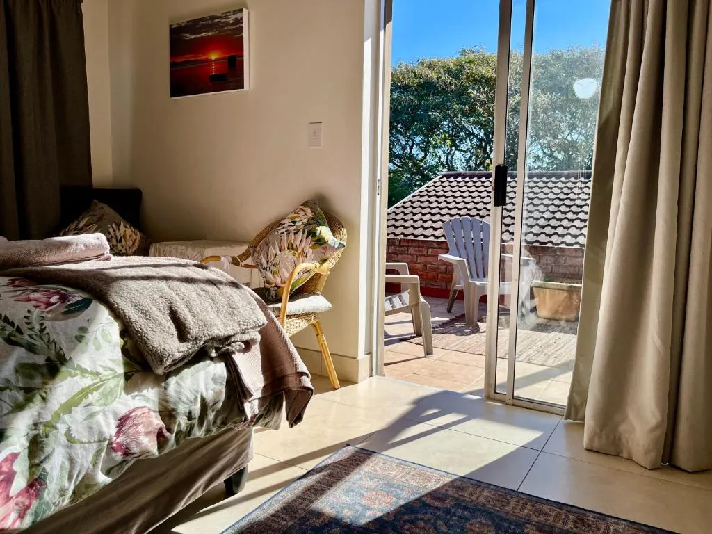Bedroom with floral bedspread opening onto a private patio with garden chairs