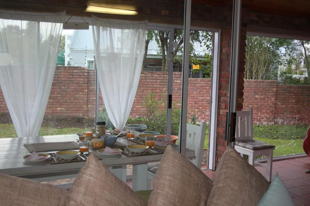 Breakfast table set with juice and cereal beside glass doors onto a walled garden