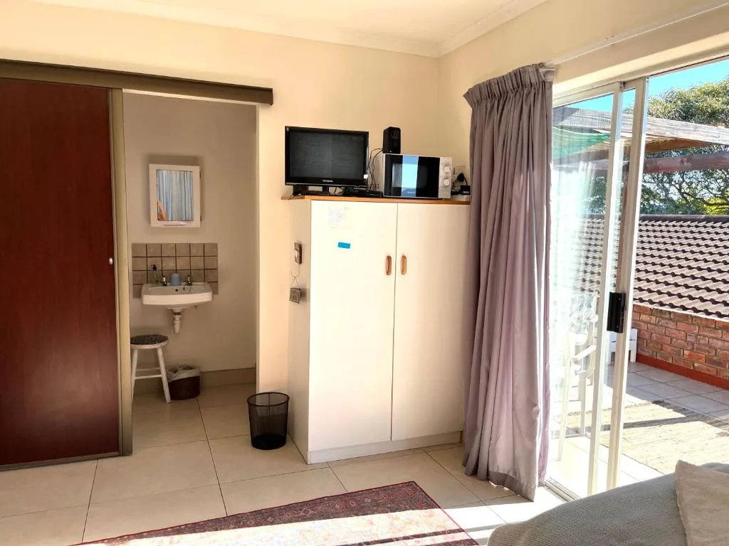 Room with ensuite basin nook, wall-mounted TV and a sliding door onto the patio