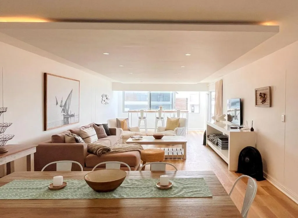 Open-plan dining table with a sectional lounge and breakfast bar beyond