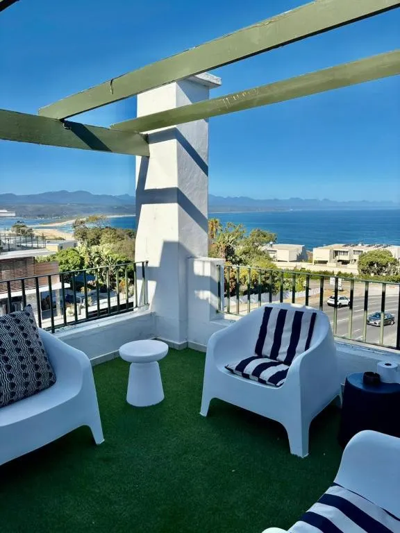 Rooftop terrace with striped-cushion chairs and a clear daytime view over the bay and coastline