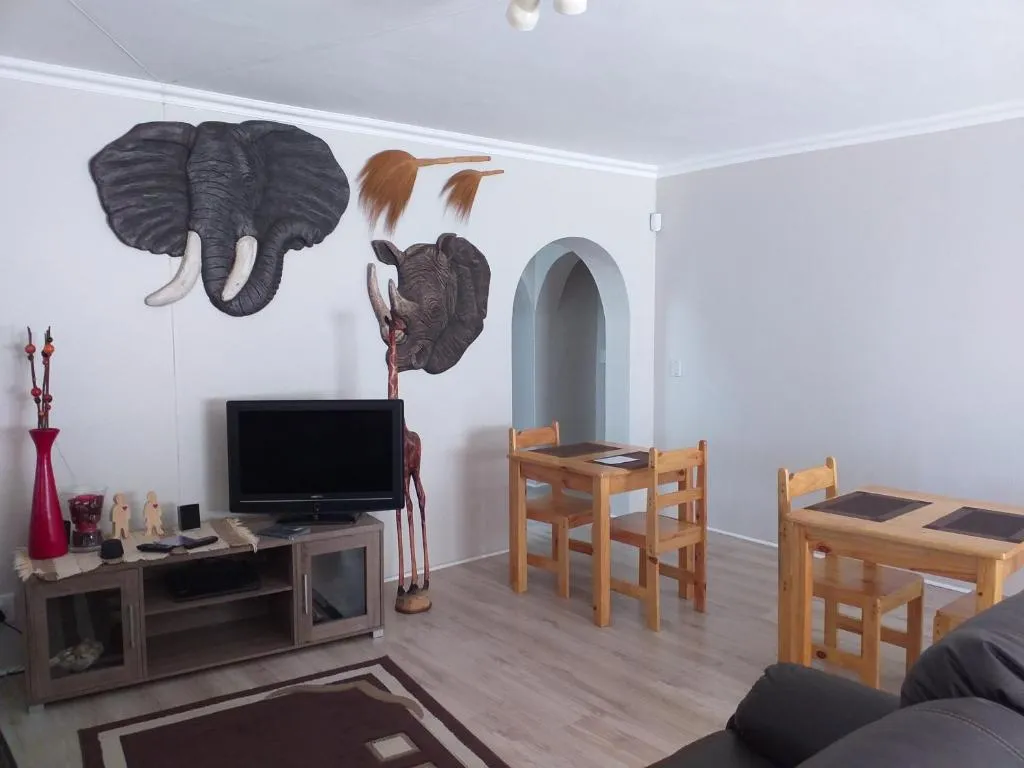 Living area with dining tables, sofa and wall-mounted elephant and rhino carvings