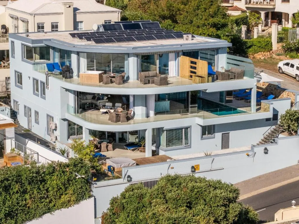 Aerial view of a multi-level modern villa with rooftop solar panels and a terrace pool