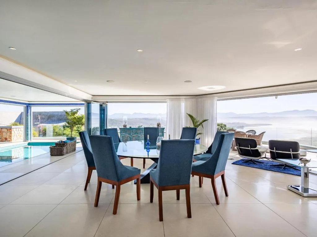 Dining table with blue wingback chairs set against a full-width ocean view