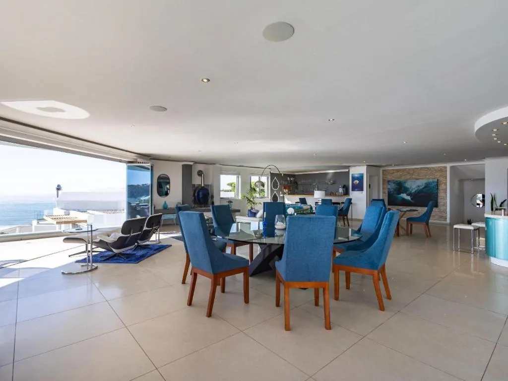 Open-plan dining and lounge area with wraparound glazing over the coastline