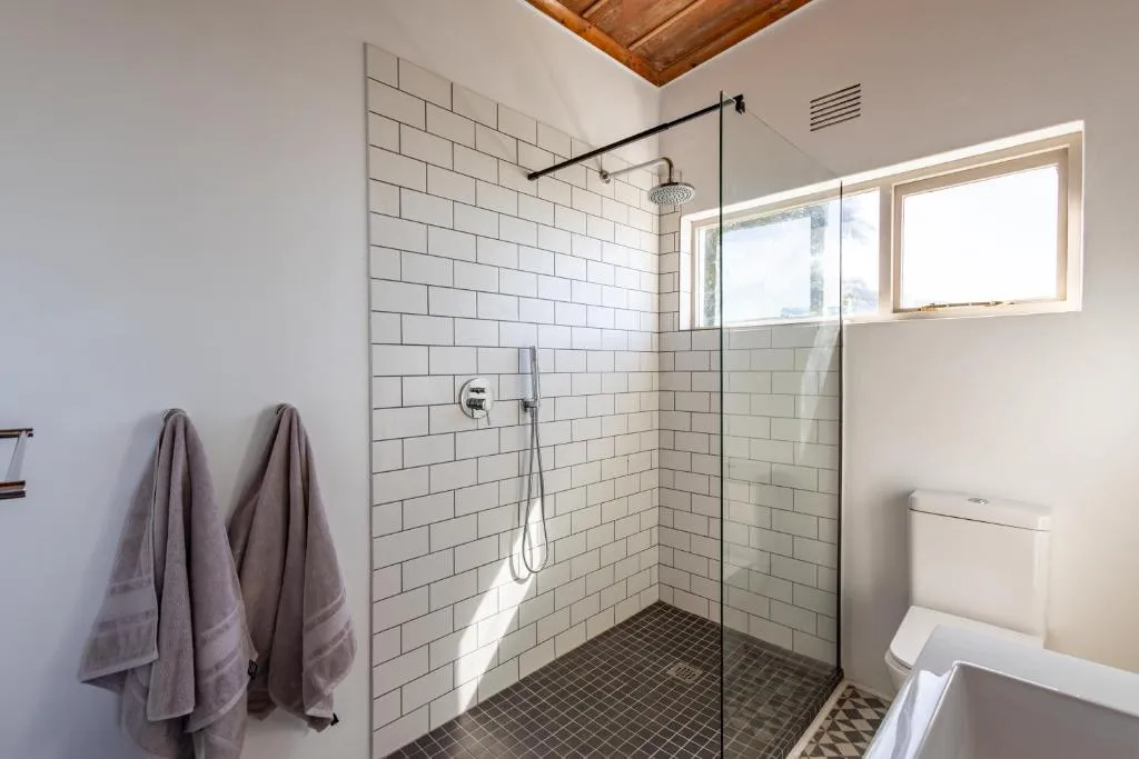 Bathroom with a walk-in subway-tiled shower, toilet and a small window