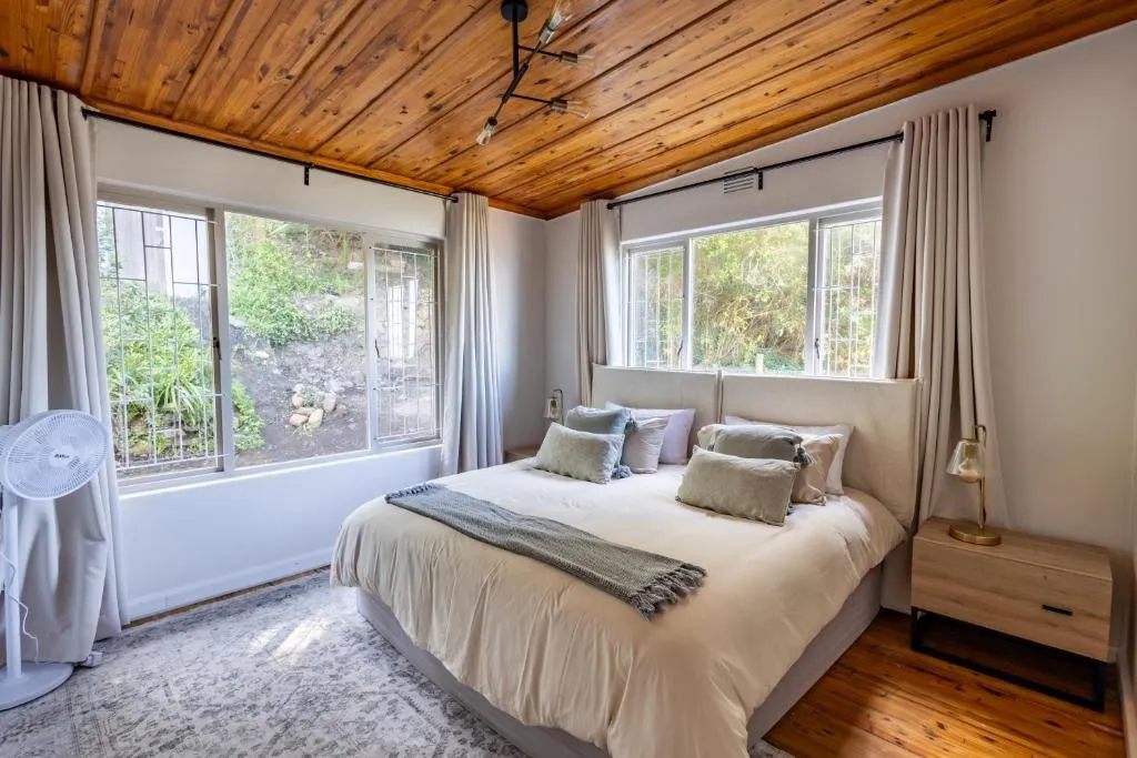 Bedroom with a timber ceiling and barred windows onto a rockery garden