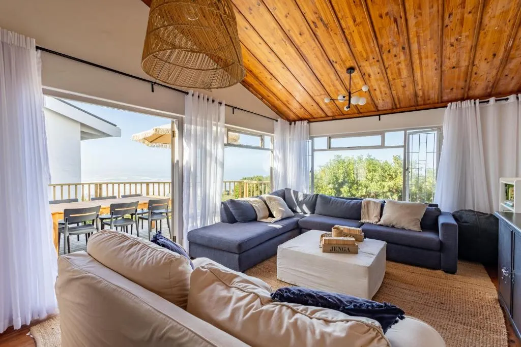 Living room opening through sliding doors onto a deck with a clear sea view