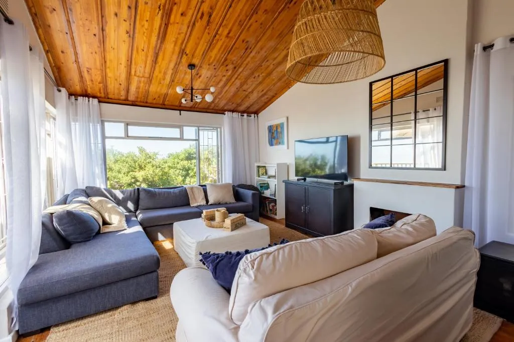 Living room with a sectional sofa and wall-mounted TV under a vaulted timber ceiling