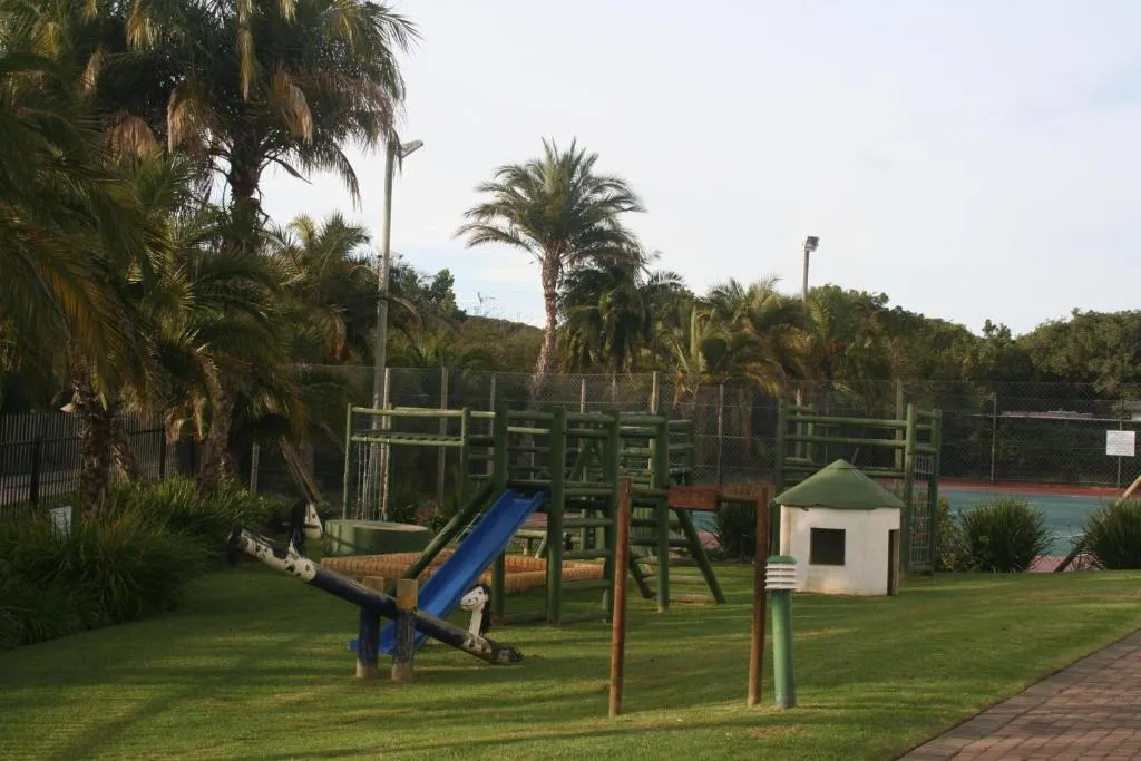 Shared estate children's playground with a slide and jungle gym beside a tennis court