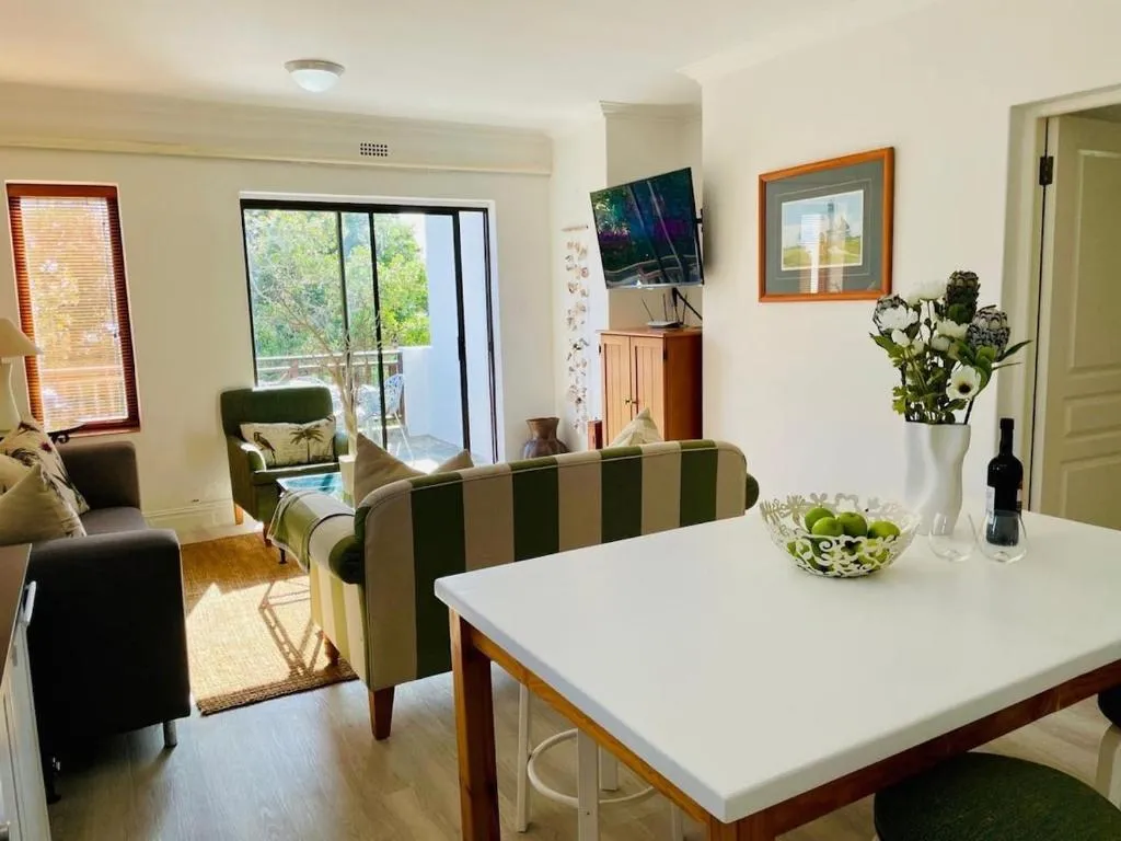 Dining table with fresh flowers beside a lounge and sliding doors onto a balcony