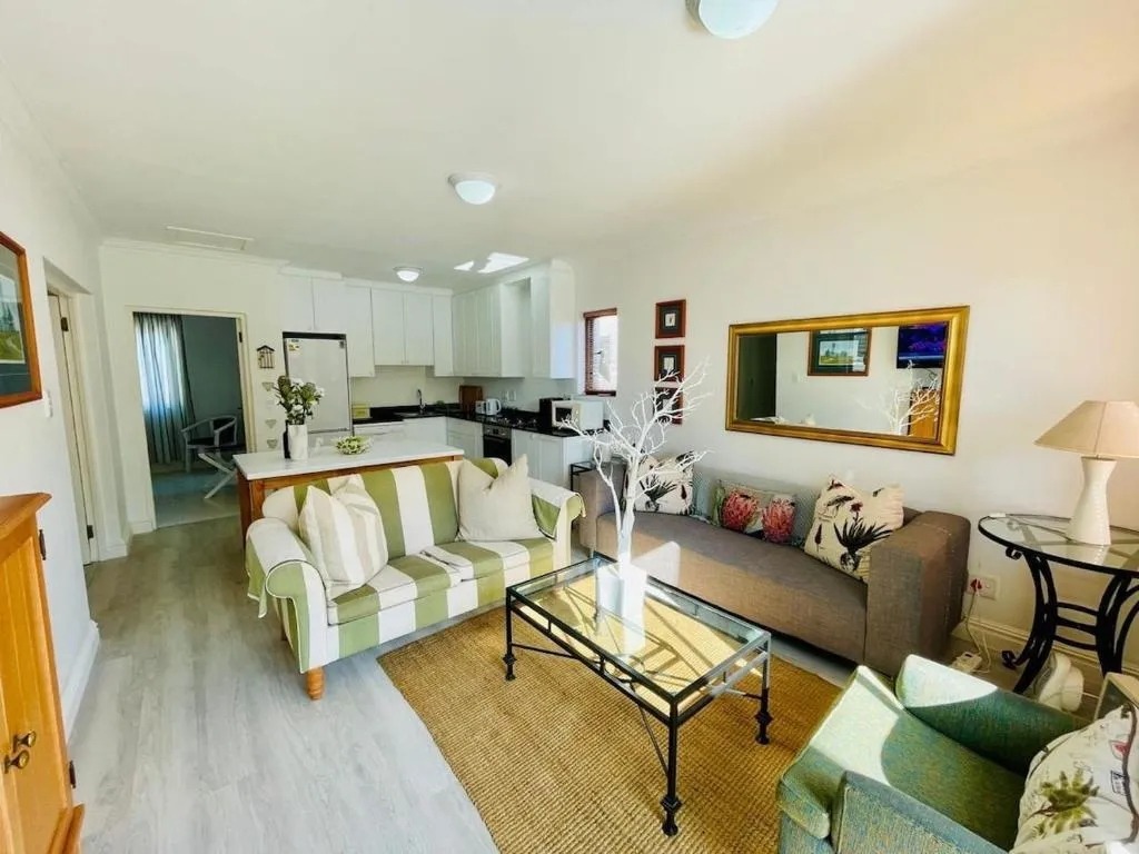 Open-plan living room with a striped sofa opening through to a white kitchen