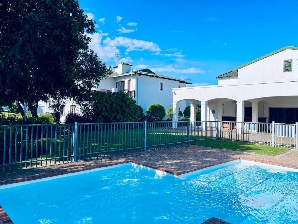 Shared estate pool with a fenced lawn and the clubhouse building behind