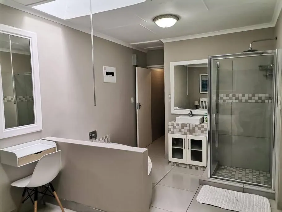 En-suite bathroom with a glass-walled shower, tiled vanity unit, and a small corner desk