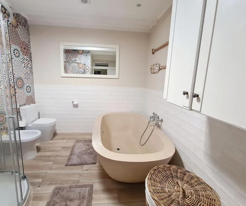 Bathroom with a freestanding bath, mosaic tile mirror surround and separate bidet