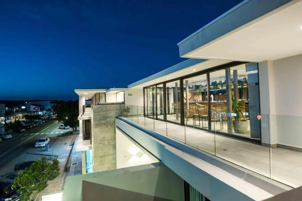 Evening view along the building's balcony with a glass-fronted communal lounge beyond