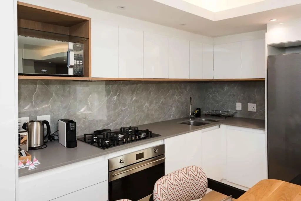 Kitchenette with a marble-look splashback, gas hob and stainless oven